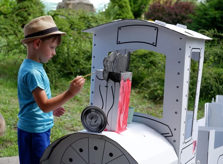 Chłopiec kolorujący zabawkę z kartonu flamastrami