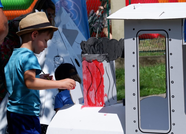 Dzieci bawiące się pomalowaną kartonową lokomotywą, integrując zabawę z nauką.