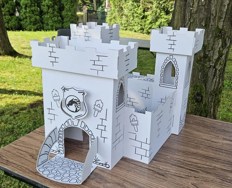 Zamek z tektury na stole w ogrodzie, gotowy do zabawy i kolorowania.