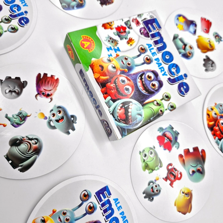 Emocje Ale Pary - zestaw kart z potworkami i opakowaniem: Pudełko gry "Emocje - Ale Pary" oraz kilka okrągłych kart z ilustracjami potworków wyrażających różne emocje.