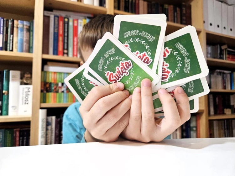 Dziecko trzymające w dłoniach karty do gry Piotruś / Pamięć – Święta z motywem bożonarodzeniowym, Alexander, wiek 4+.