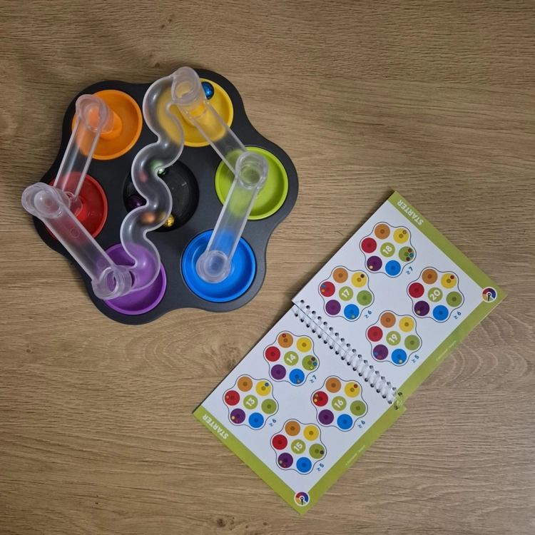 Widok gry Dropzone z planszą i otwartą książeczką z zadaniami.