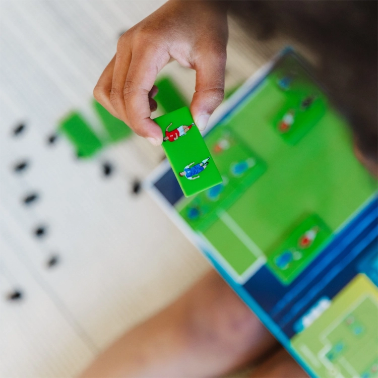 Dziecko trzymające element gry Goool! z ilustracją zawodników.