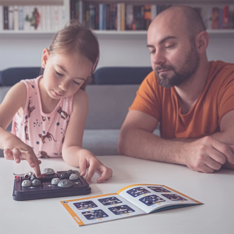 Dziewczynka grająca w Gwiezdną Ucieczkę z dorosłym przy stole.