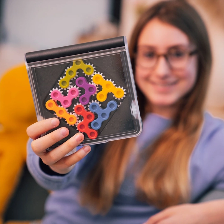 Dziewczynka trzymająca planszę IQ Gears z ułożonymi zębatkami.
