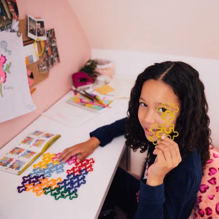 Dziewczynka trzymająca żółty element gry IQ Matrix w kształcie puzzli.