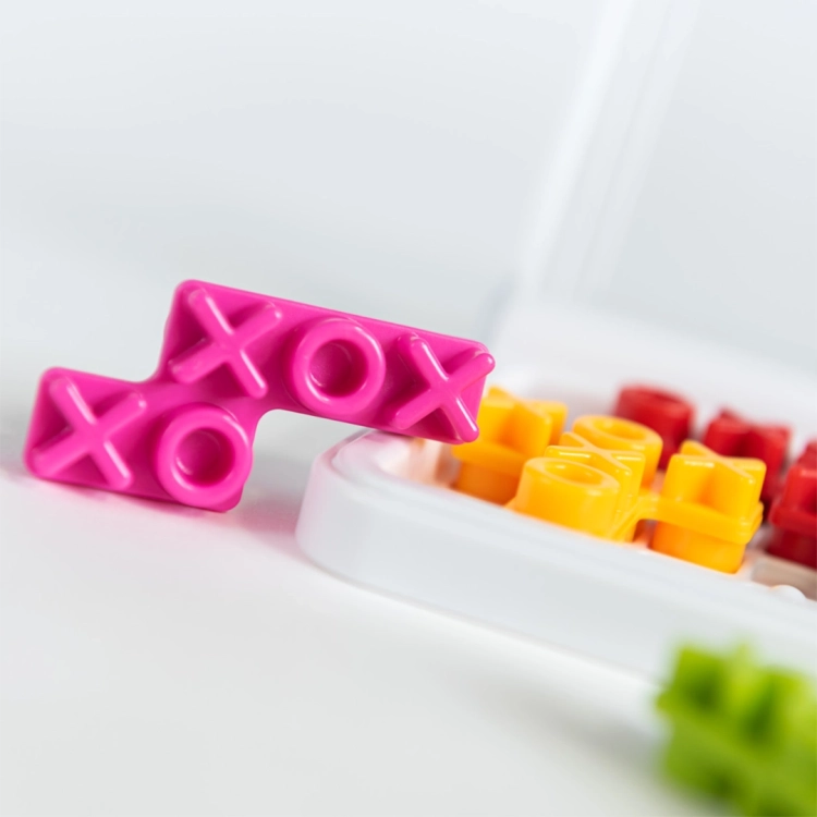Różowy element w kształcie "X" i "O" na białej planszy gry IQ XOXO.
