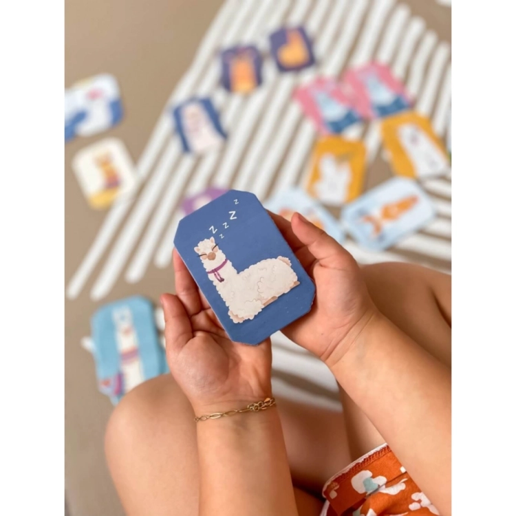 Dziecko trzymające karty z grą memo Lamy i Jednorożce.