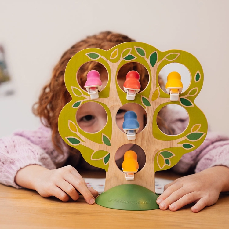 Dziecko ogląda grę Ptasie Figle przez drewniane drzewko