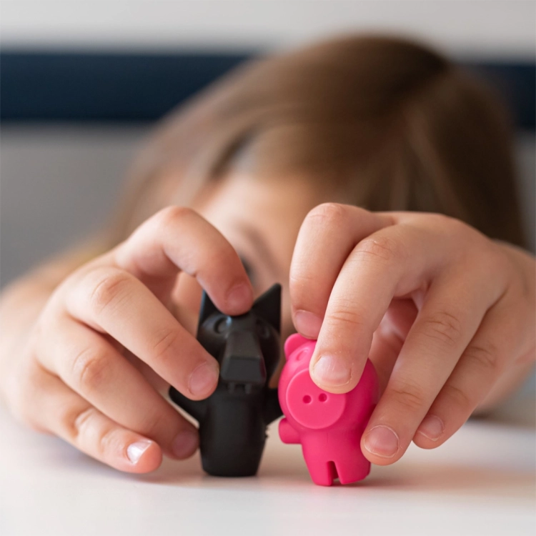 Dziecko bawiące się figurkami wilka i świnki z gry Trzy Małe Świnki – Smart Games