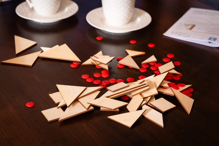 Drewniane elementy i czerwone żetony gry tangram silver na stole.
