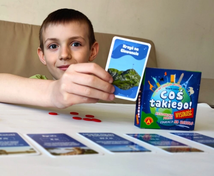 Dziecko trzyma kartę z pytaniem "Krzyż na Giewoncie" z gry "Coś takiego! Wysokość".