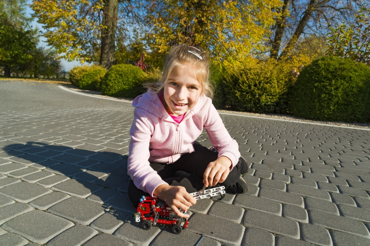 Dziewczynka bawiąca się modelem straży pożarnej na zewnątrz.