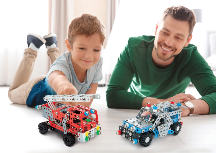 Chłopiec i mężczyzna bawiący się modelami straży pożarnej i policyjnego auta Mały Konstruktor.