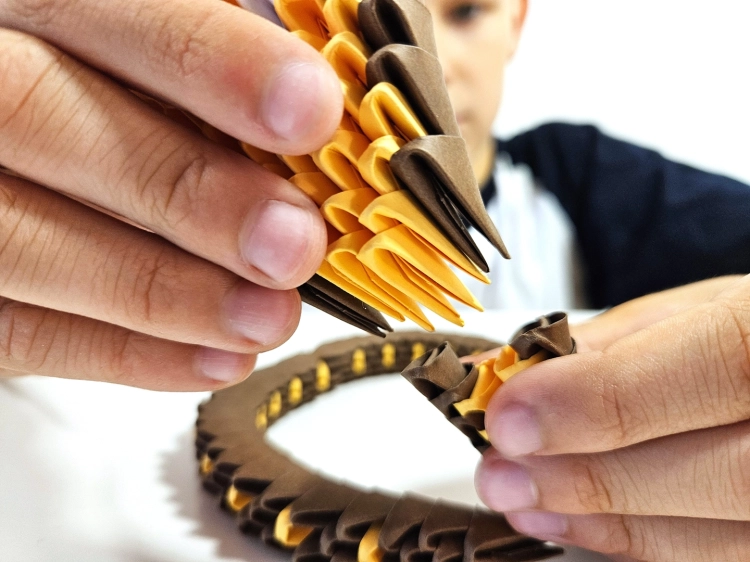 Chłopiec składający model kobry Origami 3D marki Alexander.