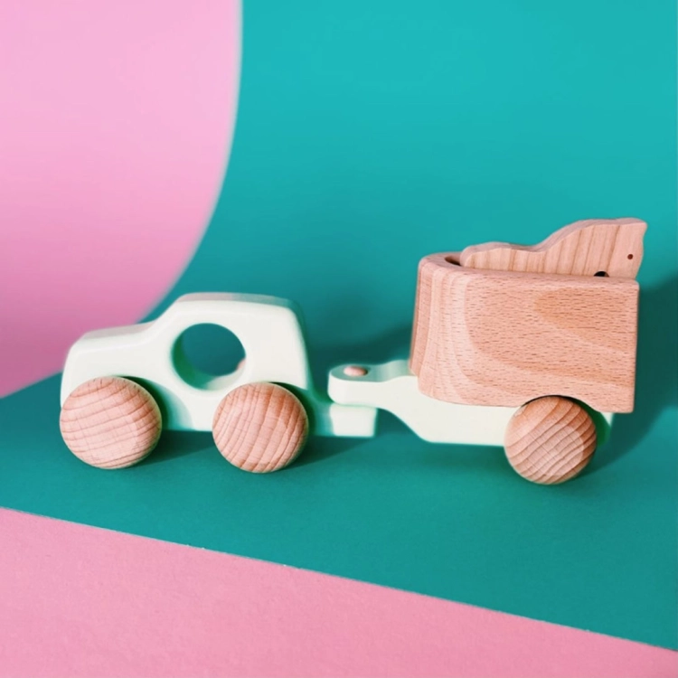 Drewniany samochodzik z konikiem na tle pastelowych kolorów.