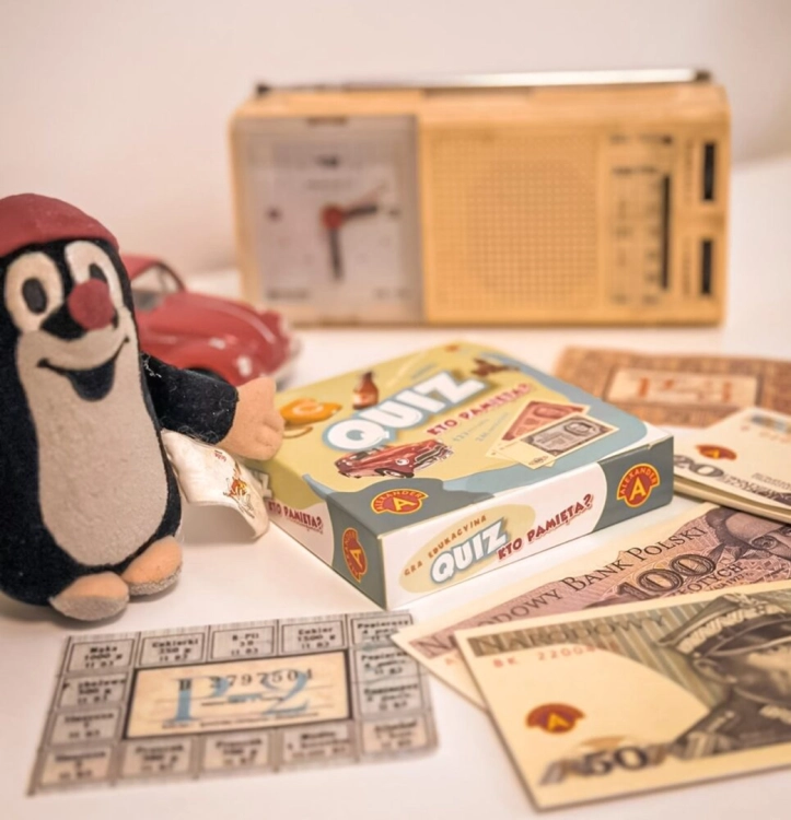 Opakowanie gry edukacyjnej Quiz Kto Pamięta? od Alexander na tle charakterystycznych gadżetów z PRL