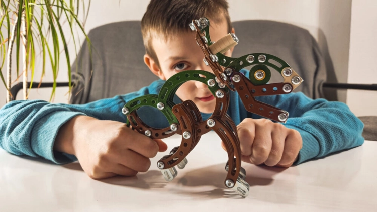 Chłopiec bawi się metalowym modelem dinozaura Triceratops.
