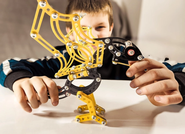 Dziecko trzyma metalowy model Pterodaktyla z zestawu Mały Konstruktor Alexander.