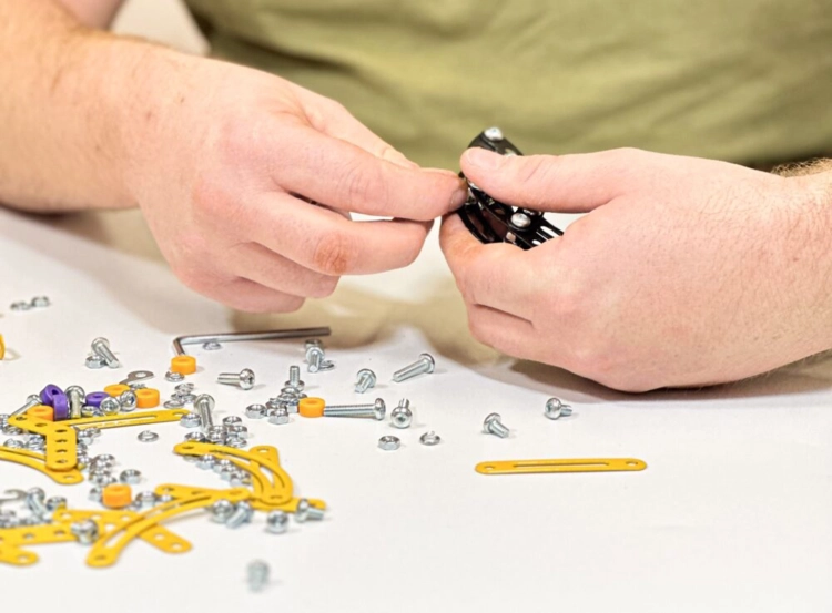 Proces składania Pterodaktyla z elementów metalowych i śrubek.