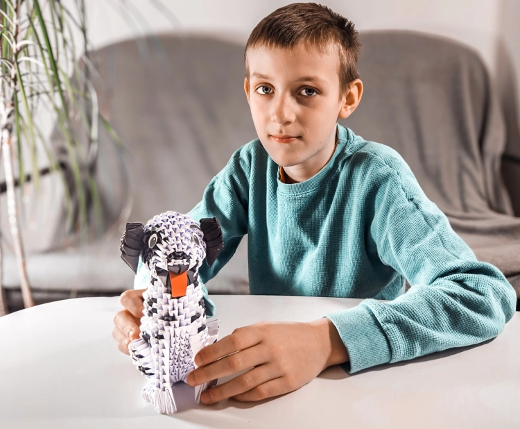 Chłopiec trzymający gotowy model origami 3D pieska