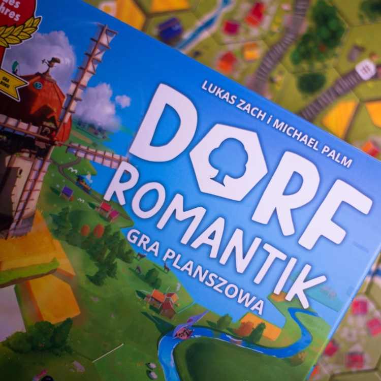Zbliżenie na elementy gry Dorfromantik – Kolorowe kafelki planszy z torami kolejowymi, domkami i rzeką.