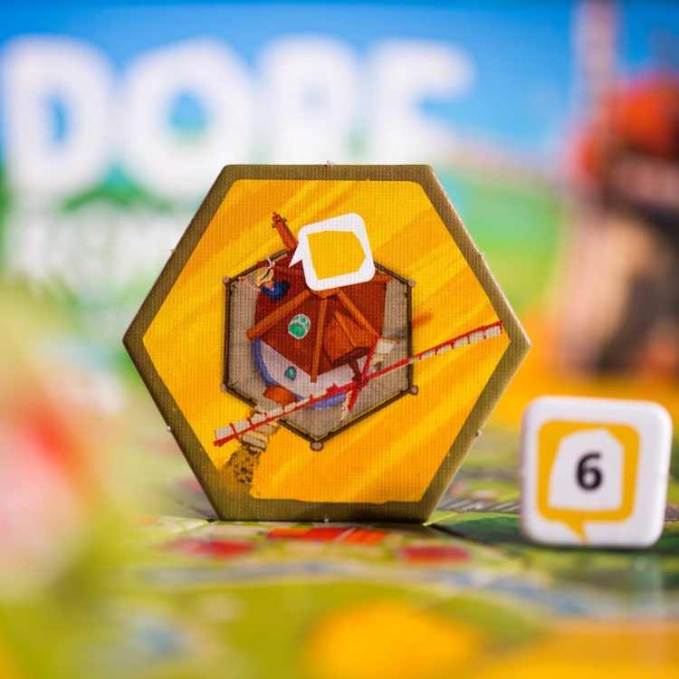 Kafelek z domkiem w Dorfromantik – Pojedynczy heksagonalny kafelek z ilustracją drewnianego domu na polu pszenicy.