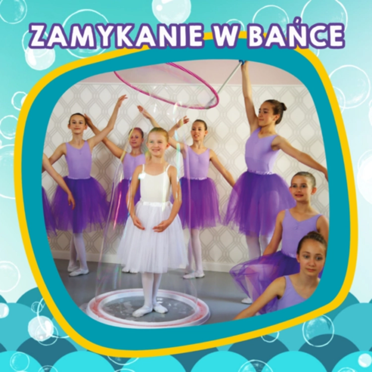 Pokaz zamykania w bańce – dziewczynka w białej sukience otoczona ogromną bańką, w tle grupa tancerek.