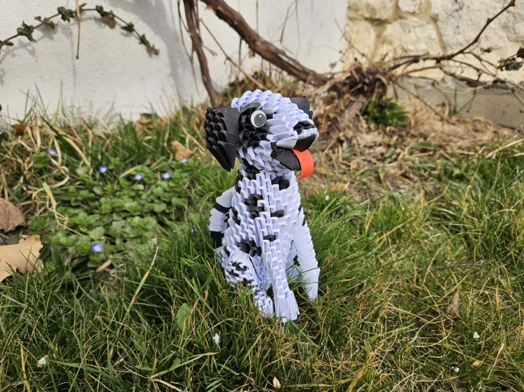 origami 3D pieska dalmatyńczyka wykonany z papieru stojący w ogrodzie na trawie