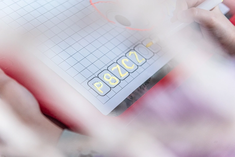 carotina-tablica-led-lisciani-3plus (4).webpDziecko piszące słowo "pszczola" na podświetlanej tablicy edukacyjnej