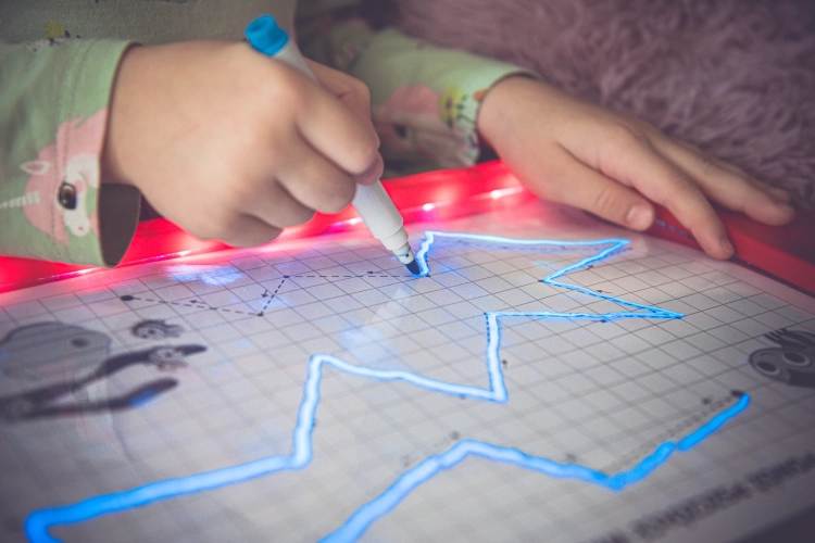 Dziecko rysujące gwiazdkę na tablicy LED Carotina z efektem świetlnym