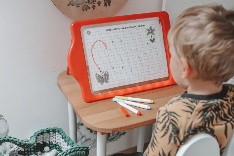 Chłopiec przy biurku korzystający z tablicy LED Carotina do nauki pisania