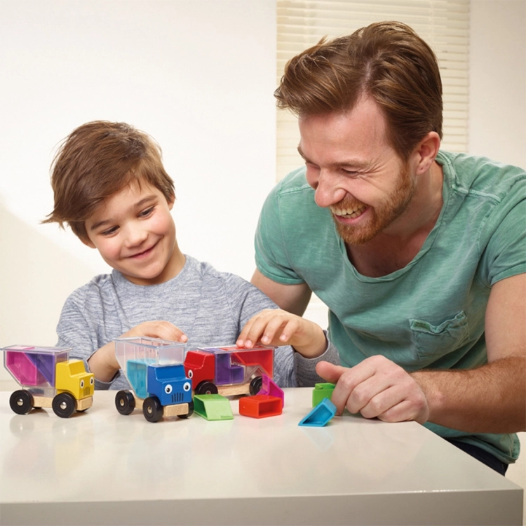 Chłopiec i tata bawią się grą 3 Traki SmartGames, układając klocki w ciężarówkach