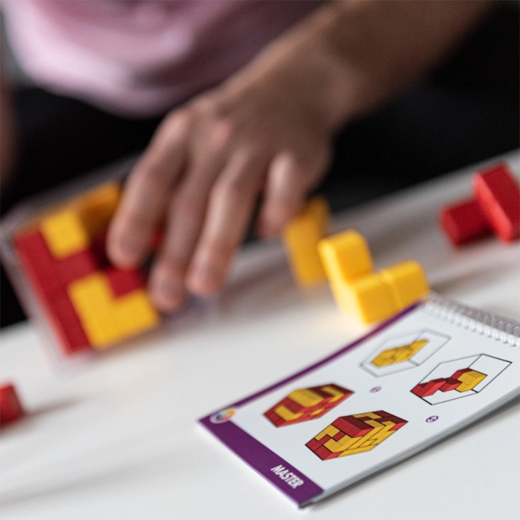 Blok w Blok SmartGames – rozgrywka – gracz układa czerwone i żółte klocki w przezroczystej kostce.