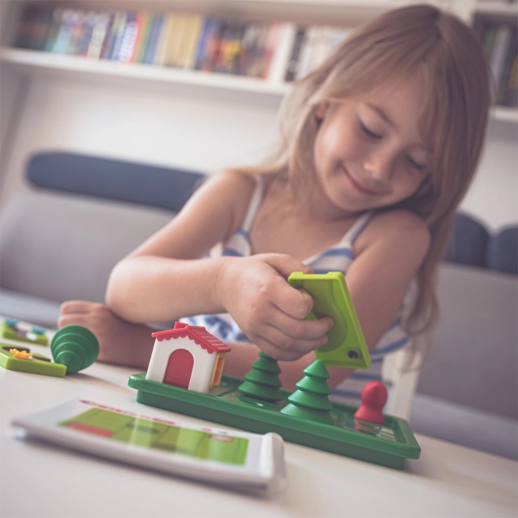 Dziewczynka układa trasę dla Czerwonego Kapturka w grze SmartGames.