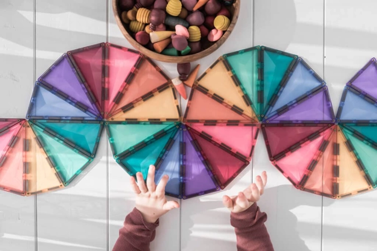 Ręce dziecka przy kolorowych kołach złożonych z trójkątów równoramiennych.