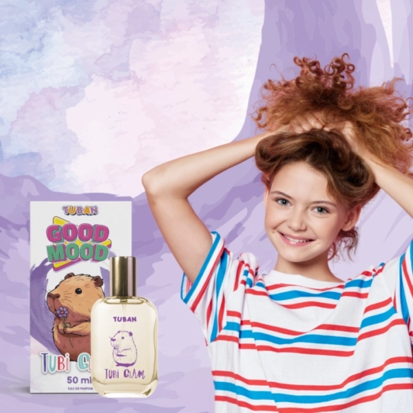 Dziewczynka uśmiecha się z rękami we włosach obok perfum Tubi Glam Good Mood i opakowania z rysunkiem chomika.