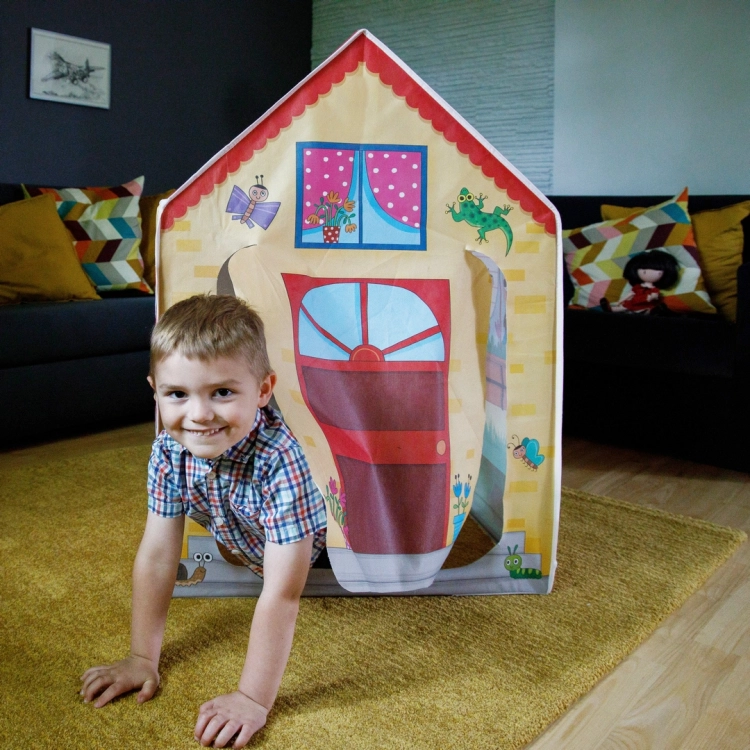 Chłopiec wychodzący z domku Montessori przez otwór w drzwiach