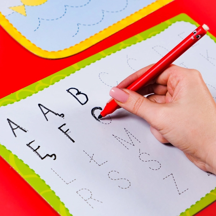 Pisanie liter alfabetu na specjalnej tabliczce za pomocą czerwonego pisaka.