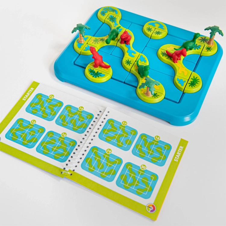 Plansza gry Dinozaury – Tajemnicza Wyspa z rozłożonymi elementami i książeczką z zadaniami. Widoczne są kolorowe wyspy, czerwone i zielone figurki dinozaurów oraz zadania o różnym poziomie trudności.