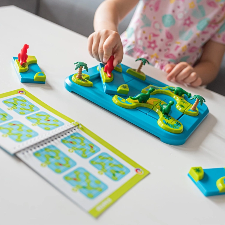Dziecko układa elementy gry na planszy, korzystając z instrukcji z zadaniami. Kolorowe wyspy i dinozaury przyciągają uwagę, tworząc wciągającą atmosferę zabawy.