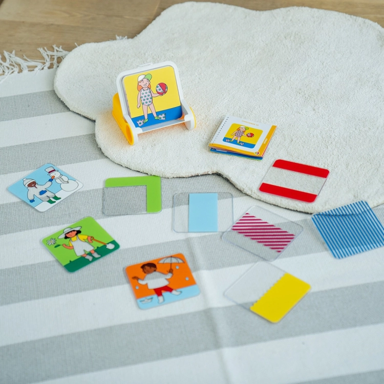 Rozłożone elementy gry Dress Code na dywanie – karty, płytki i ramka.