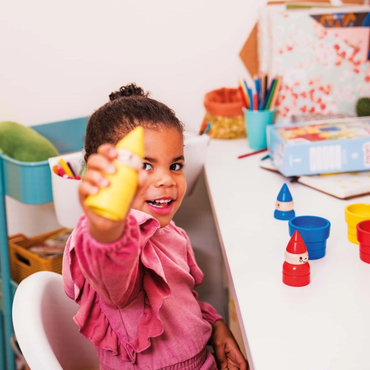 dziewczynka prezentująca żółtego gnomka z gry logicznej Gnomki i Domki