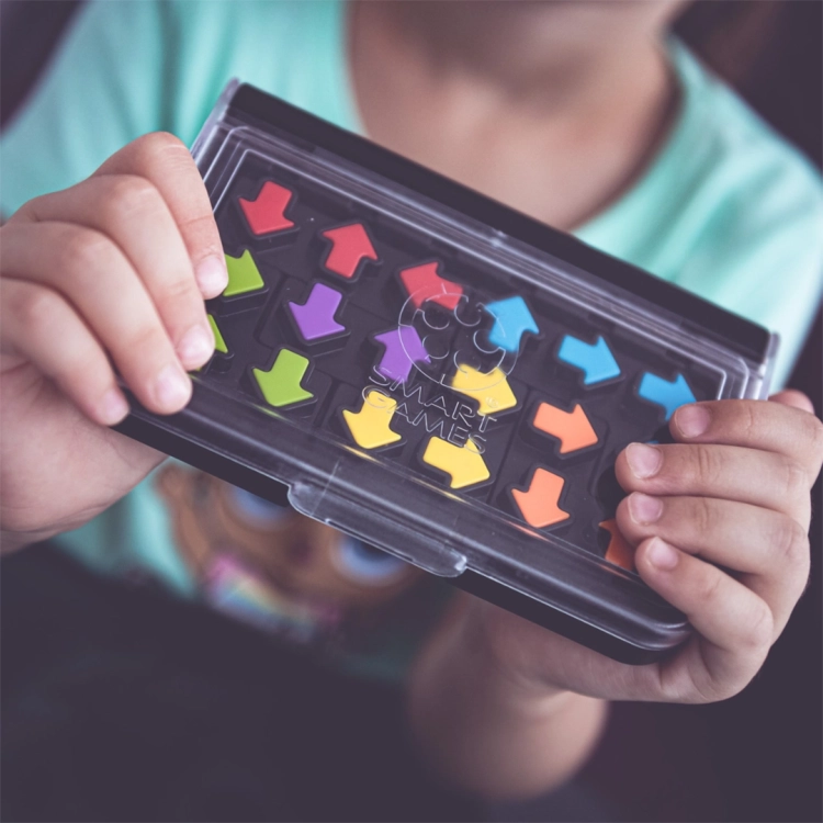 dziecko trzymające grę IQ Arrows Smart Games w przezroczystym opakowaniu