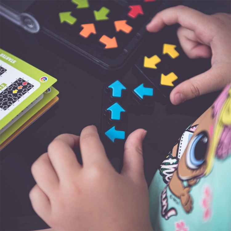dziecko układające niebieskie strzałki na planszy IQ Arrows Smart Games