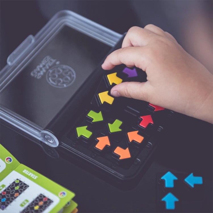 dziecko rozwiązujące zadania z gry logicznej IQ Arrows z książeczką