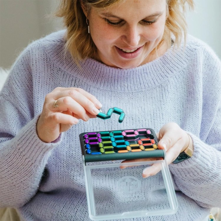 Kobieta układająca niebieski element w grze IQ Digits od Smart Games.