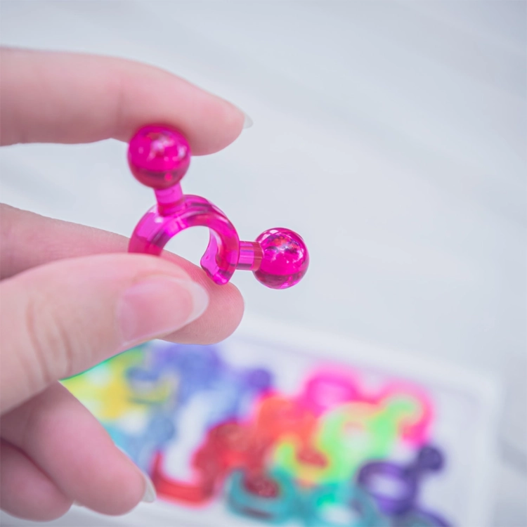 Różowy element IQ Link trzymany w palcach na tle gry.