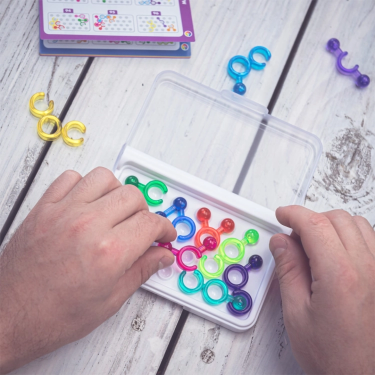 Osoba dorosła grająca w IQ Link, układa elementy na planszy.