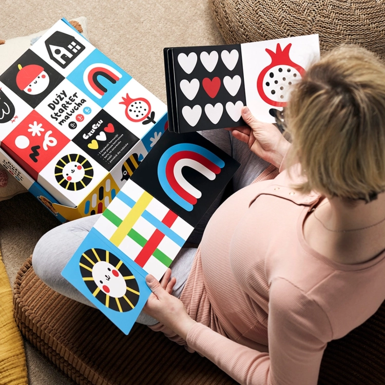 Ciężarna kobieta ogląda książeczkę z zestawu Duży starter malucha CzuCzu